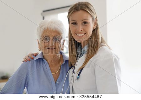 Portrait of elderly woman with nurse at home