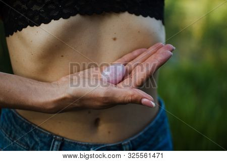 Adult Woman Is Holding Pink Quartz Yoni Egg For Vumfit, Imbuilding Or Meditation Outdoors Over Her N