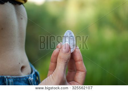 Side View Of Adult Woman Holding Transparent Violet Amethyst Yoni Egg For Vumfit, Imbuilding Or Medi