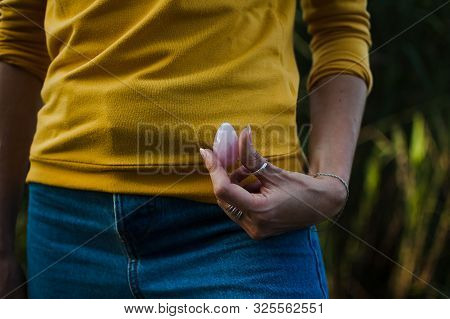 Adult Girl In Yellow Shirt And Blue Jeans Is Holding Pink Quartz Yoni Egg For Vumfit, Imbuilding Or 