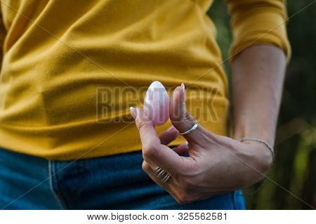 Adult Girl In Yellow Shirt And Blue Jeans Is Holding Pink Quartz Yoni Egg For Vumfit, Imbuilding Or 