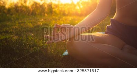 Young Woman Practicing Yoga On The Beach At The Sunset. Meditation Process And Female Happiness Conc