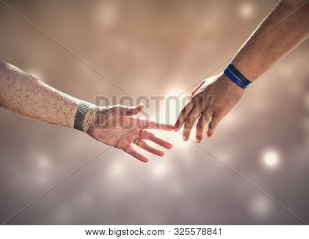 Two generations connecting. The hands of an old white woman and a young black man touching. Concept image about age, connections, diversity, race and cultures