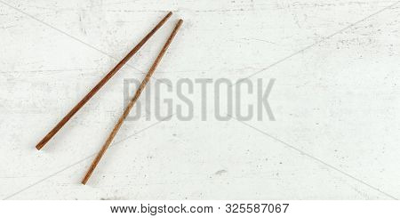 Top Down View - Pair Of Dark Wood Chopsticks On White Board. Can Be Used As Banner For Asian / Chine