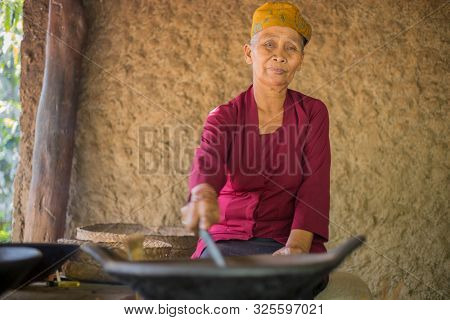 Bali, Indonesia - September 13 2019: Old woman roasting luwak coffee beans in Ubud. Luwak coffee is very expensive and famous Balinese cofee