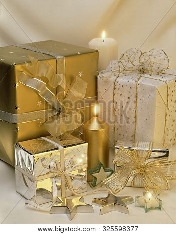 A Bunch Of Wrapped Gifts With Lit Candles And Stars