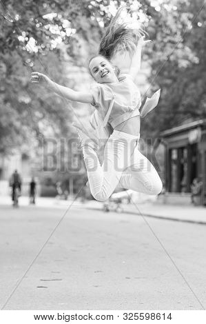 Bouncy And Energetic. Energetic Little Child In Motion On City Street. Lively Small Girl Jumping Wit
