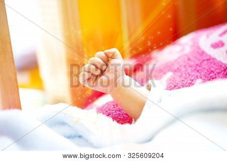 Hand Of An Energetic Newborn Baby With Light Blue And Pink Blanket And Baby Bed. Close Up.