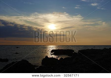 岩の多いビーチに沈む夕日