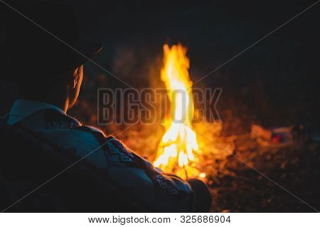 Quiet Tranquil Time In The Night By The Campfire,soft Focus. Man In Traditional Native American Ponc