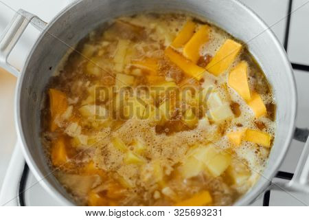 Pumpkin Soup Cooking In Sausepan In The Kitchen On The Stove. Autumn Traditional Food