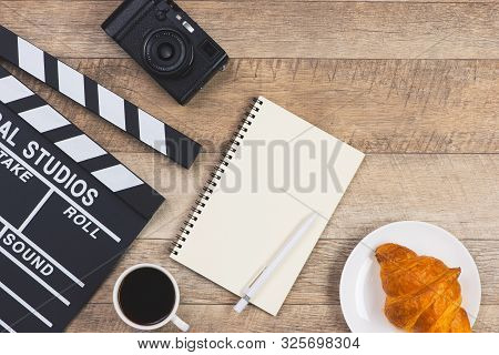 Movie Clapper With Paper, Pen, Cake And Cup Of Coffee On Wooden Planks Background