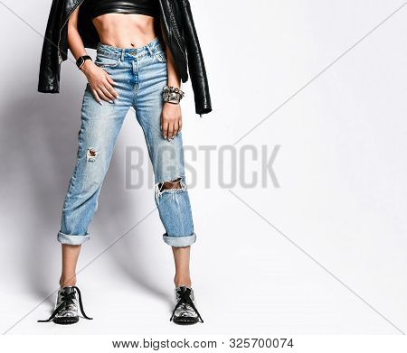 Closeup Of Brutal Style Girl Legs And Stomach In Torn Jeans, Leather Bralet, Leather Jacket And Chro