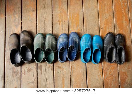 Five Pairs Of Old Family Rubber Boots On The Wooden Floor