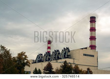 The Building Of The Chpp Is A Combined Heat And Power Plant With Pipes Against A Gloomy Sky. Chimney