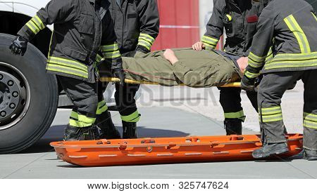 Four Firemen Charge A Wounded Person On A Stretcher After An Accident