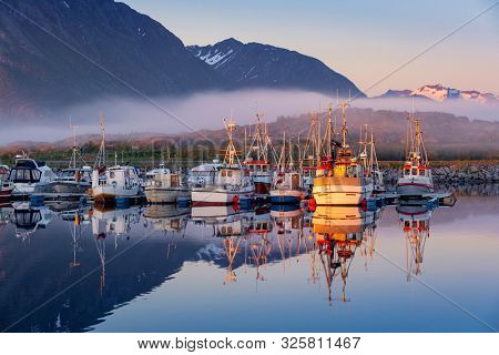 Laukvik, Lofoten Islands, Norway, Fishing boats in harbor at midnight sun, Mountain With Snow In Background