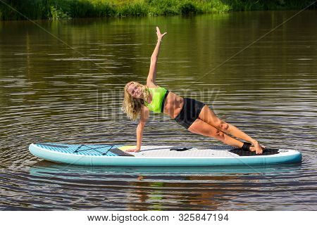 Young European Woman Planking Sideways On Sup In Lake