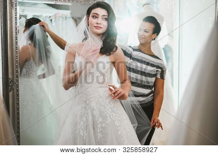 Beautifu bride choosing wedding dress in a wedding salon