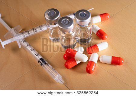 Close Up Of A Hypodermic Needle And Red Pills
