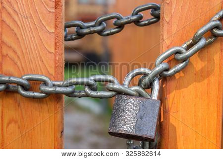 Steel Chain With Padlock Wound Around The Boards Of A Bright Fence