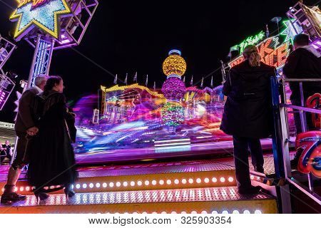 Munich, Germany, 2019 September 24: Visitors Enjoy The View Of An Amusement Park Ride At Night. Brea