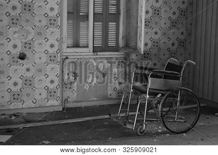 Antique Wheelchair In Abandoned House Interior. Black And White.