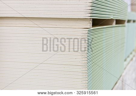 Gypsum Plasterboard In The Pack. The Stack Of Gypsum Board Preparing For Construction. Pallet With P