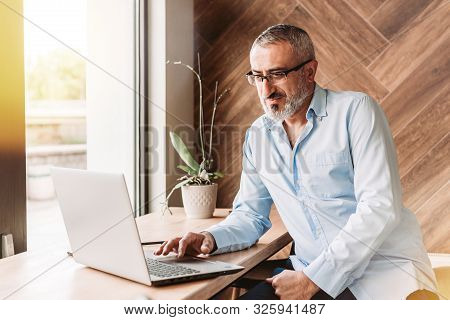 Handsome Middle Aged Man Working On Computer In A Cafe. Business, Modern Concept