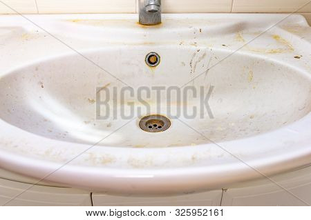Old Dirty Washbasin With Rust Stains, Limescale And Soap Stains In The Bathroom With A Faucet, Water