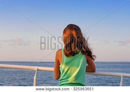 A Little Girl In Green Tank Top Leaning On The Railing While Looking At The Horizon