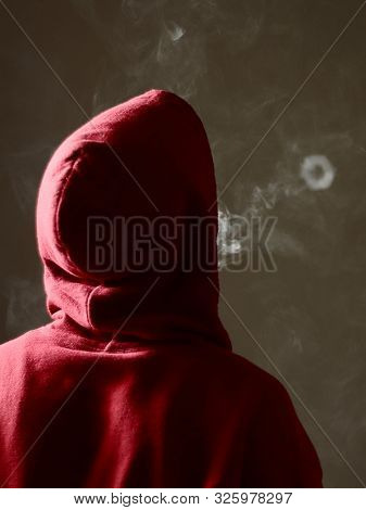 Young Male In Red Hoodie Vaping Smoking, Blows A Single Smoke Ring, Isolated Rear View