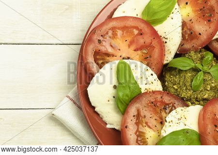 Caprese Salad In A Plate Over Wooden Background. Fresh Tomato And Mozzarella Cheese With Basil Leave