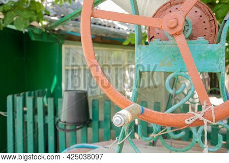 An Old Water Well With A Bucket In The Garden, A Metal Handle For Lifting Water From The Ground. Vil