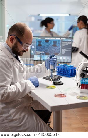 Scientist Doing Genetic Experiment Using Blood Sample On Micropipette Dropped On Petri Dish. Team Of