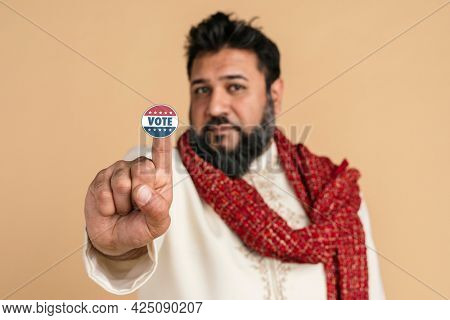 An Indian man in a kurta showing a voting sticker