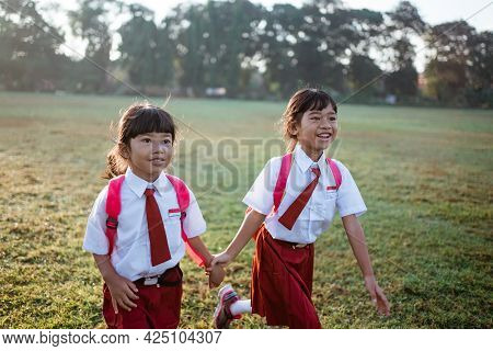 Happy Female Asian Primary School Student Walk Together