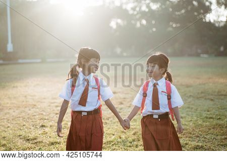 Happy Female Asian Primary School Student Walk Together