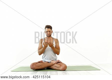 Male Yoga Maditates In Classical Pose In Studio Over White Background