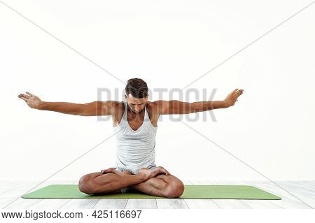 Male Yoga Maditates In Classical Pose In Studio Over White Background