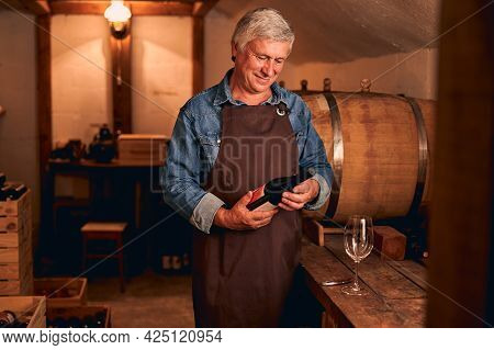 Joyful Man With Bottle Of Wine Standing In Wine Cellar