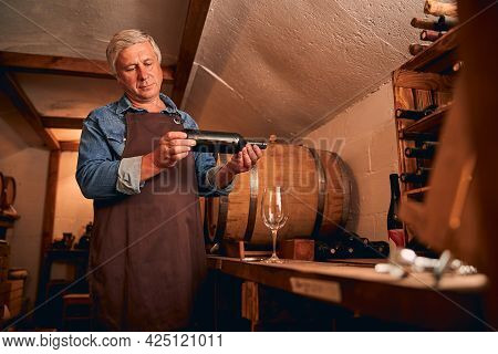 Handsome Man With Bottle Of Wine Standing In Wine Cellar