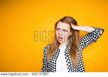 A Young Girl With Long Hair Grabs Her Head With Her Hand From A Headache, Opening Her Mouth