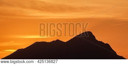 The Profile Of Mount Pizzocolo With An Orange Sunset In The Background.