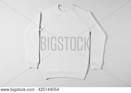 White Jacket Lying On A Light Background In The Studio. Light Hoodie For Men And Women. Bomber Witho