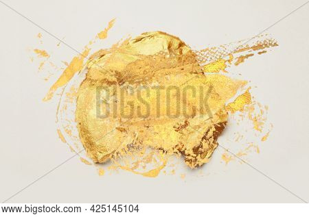 Gold glitter and bronze color abstract blot. Abstract torn piece of metal leaf (potal) paper on light background. 