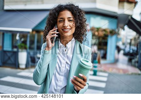 Young hispanic business woman wearing professional look smiling confident at the city speaking on the phone
