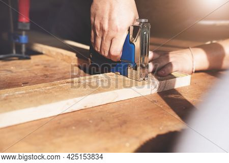 Entrepreneur Woodwork Holding A Tacker To Assemble The Wood Pieces As The Customer Ordered.