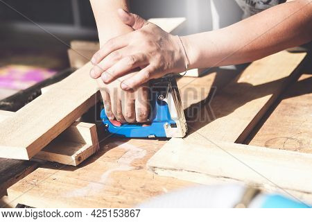 Entrepreneur Woodwork Holding A Tacker To Assemble The Wood Pieces As The Customer Ordered.