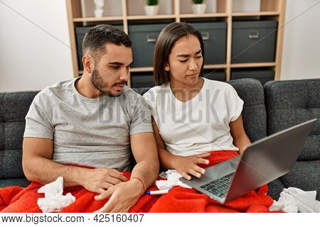 Young latin ill couple having medical teleconsultation using laptop at home.